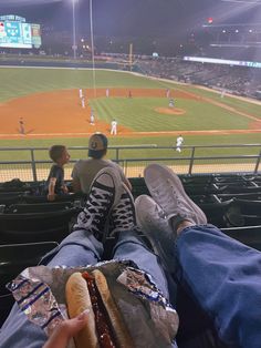 a man sitting in the stands at a baseball game eating a hot dog