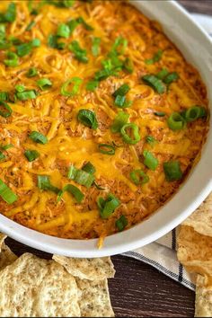 a casserole dish with green onions, cheese and tortilla chips on the side