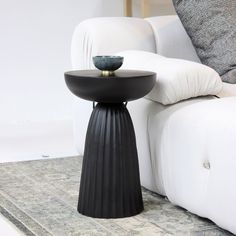 a black table sitting on top of a rug next to a white couch