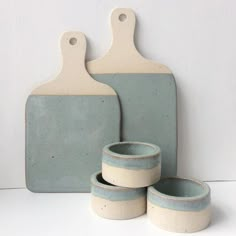 three ceramic dishes and two cutting boards on a white counter top with a gray background