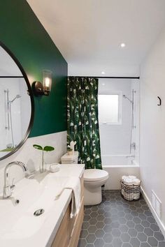 a bathroom with green and white walls, tiled flooring and a large mirror on the wall