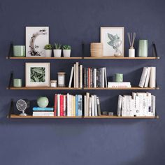 three wooden shelves with books and pictures on them against a blue wall in a living room