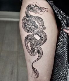 a woman's thigh with a snake tattoo on the side of her leg,