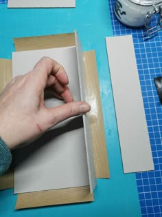 a person is cutting out some paper on a blue table with scissors and other crafting supplies