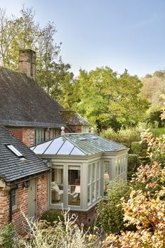 an orange brick house surrounded by greenery and trees in the sunlit garden area