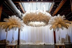 two large white chandeliers hanging from the ceiling in front of a curtained room