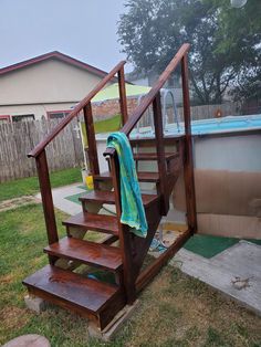 a wooden stair case next to a pool with a towel hanging on the handrail