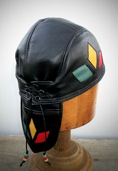 "This beautiful black lambskin leather cap is great for everyday wear!  This leather is the softest! Classy enough for dress-up!  Not JUST for bikers anymore!  Lined in 100% ORGANIC cotton for year-round comfort.  Inlaid diamond shapes on sides and tail in red/ yellow/ green w/ matching beads on cords!  Adjustable with lace-up in back. THIS SKULLCAP FITS HEAD SIZES 22\" to 22.5\" snug.   PLEASE, PLEASE, PLEASE CAREFULLY MEASURE YOUR HEAD BEFORE BUYING True flat-felled stitching for a smooth, dur Adjustable Black Motorcycle Hat, Black Fitted Leather Hat, Fitted Black Leather Hat, Black Leather Vintage Hat, Please Please Please, Leather Gear, Leather Hats, Leather Cap, Leather Conditioner