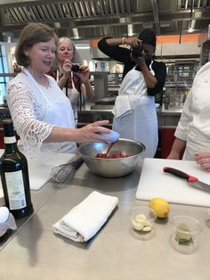 three people in a kitchen preparing food and wine