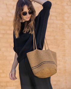 a woman wearing sunglasses and carrying a straw bag