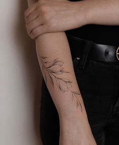 a woman's arm with a tattoo on it that has flowers and leaves on it