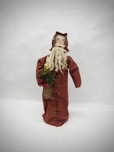 a doll with a beard and long white hair wearing a red checkered coat holding flowers