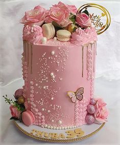 a pink cake decorated with flowers and macaroons