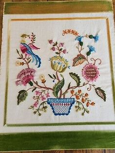 a cross stitch pattern with flowers and birds in a vase on a wooden table top