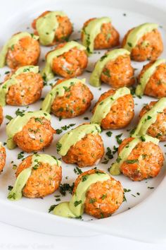 a white plate topped with crab cakes covered in green sauce