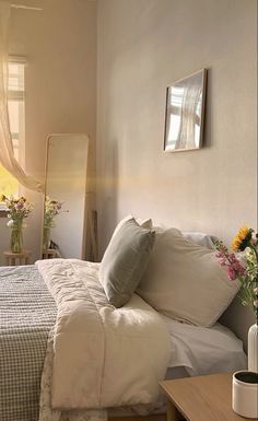 a bed with white sheets and pillows next to a window in a room filled with flowers