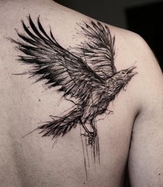 the back of a man's shoulder with a black bird tattoo on his chest