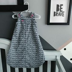 a baby's dress hanging on the wall next to a crib