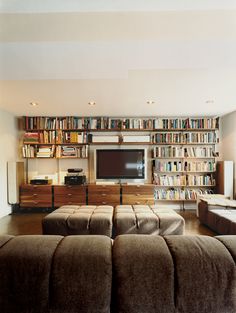 a living room filled with furniture and a flat screen tv mounted on a wall next to a book shelf