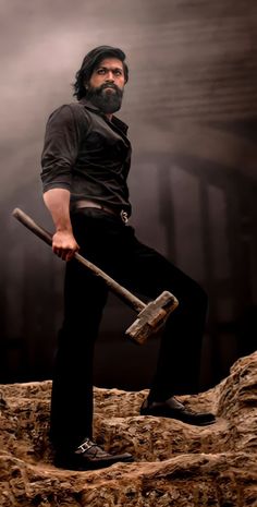 a man holding an ax while standing on top of a rock