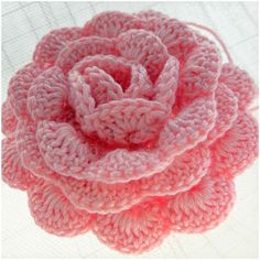 a pink crocheted flower on top of a table