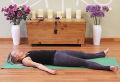 a woman is laying on her stomach in a yoga pose with purple flowers behind her