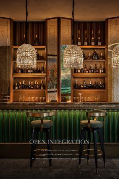 two bar stools in front of a green wall with chandeliers