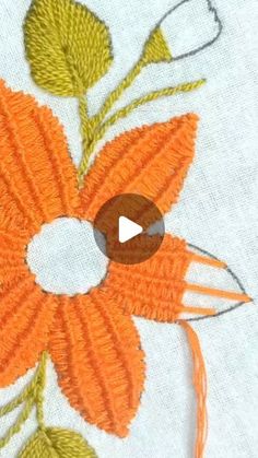 an orange flower with green leaves is stitched onto a piece of white fabric that has been sewn on