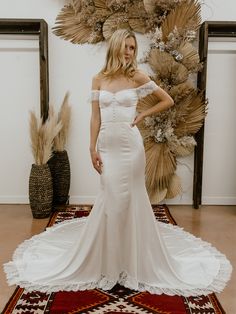 a woman in a white wedding dress standing on a rug