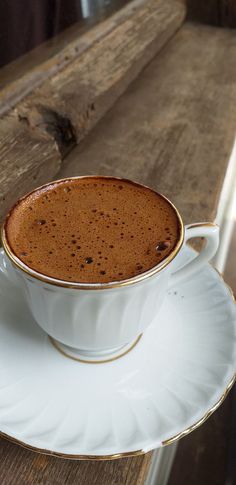 a cup of hot chocolate sitting on top of a saucer next to a wooden table