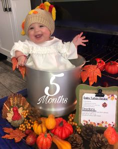 a baby is sitting in a bucket surrounded by autumn decorations and pumpkins, with the number three months written on it