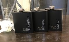 three black flasks sitting on top of a wooden table