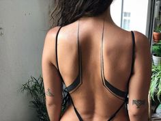 the back of a woman's body with tattoos on it