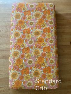 an orange and pink flowered blanket on a wooden floor with the words standard crib written below it