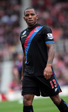 a male soccer player in black and blue uniform is on the field with a ball