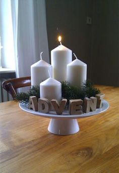 candles on a cake plate with the word adven spelled out in wood block letters