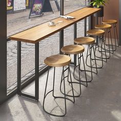 a row of stools sitting in front of a window next to a potted plant