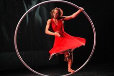 a woman in a red dress is doing a trick on a hoop with her hands