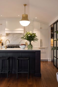 a kitchen with two stools next to an island in front of a stove top oven