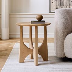 a wooden table sitting on top of a white rug next to a beige couch in a living room