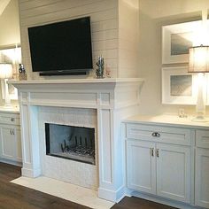 a fireplace with white cabinets and a flat screen tv on the mantel above it