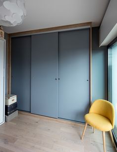 a yellow chair sitting in front of a blue closet with sliding doors on the wall