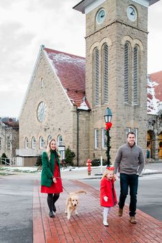 a man and woman are walking their dog down the street in front of a church