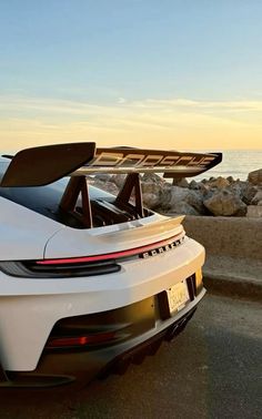 a white sports car parked next to the ocean