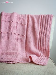 a pink knitted blanket sitting on top of a chair