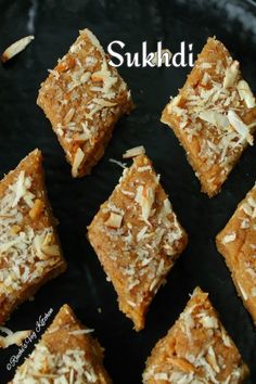 six pieces of cake sitting on top of a black plate with coconut flakes all over it