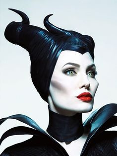 a woman with horns on her head is wearing black clothes and red lipstick, she has green eyeshades