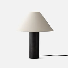 a lamp with a white shade on top of it and a cord attached to the base