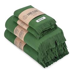 three green towels folded on top of each other with tags attached to the ends and fringes