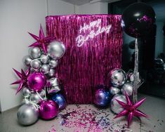 purple and silver balloons are next to a pink backdrop